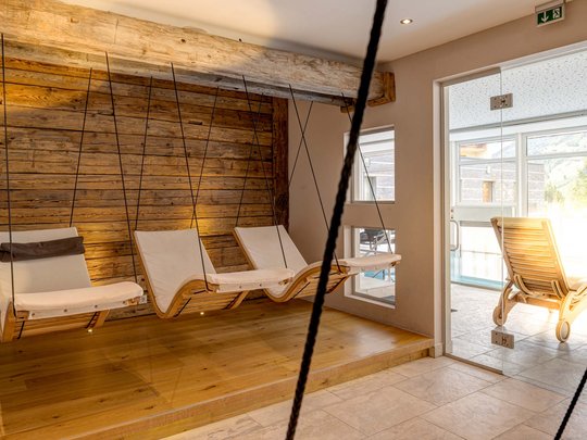 Wellnesshotel im Defereggental: Wohlfühlurlaub vom Feinsten Drei weiße Hängesessel an einer Holzwand im Innenraum