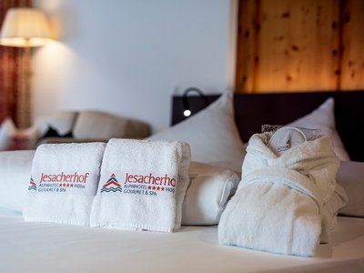 Our family hotel in Tyrol with a 4-star superior rating Fresh towels and bathrobe on bed at Jesacherhof Alpinhotel