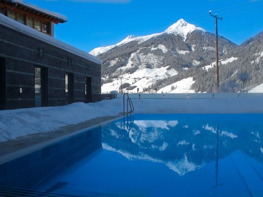 Wellnesshotel im Defereggental: Wohlfühlurlaub vom Feinsten Pool im Freien mit Blick auf schneebedeckte Berge und blauen Himmel