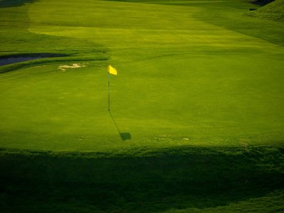Ihr Golfhotel in Tirol – Hotel Jesacherhof Grünes Golfgrün mit gelber Fahne und Schatten bei Sonnenlicht