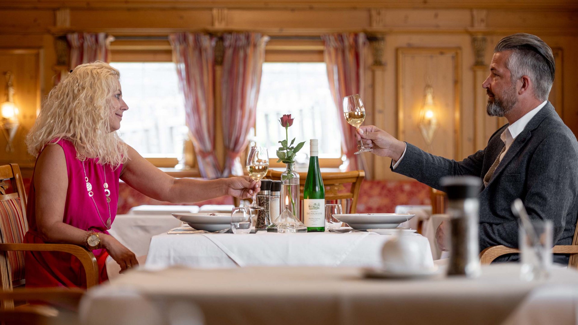 Jesacherhof: Gourmethotel in Österreich Paar stößt mit Weißwein in einem gemütlichen Restaurant an