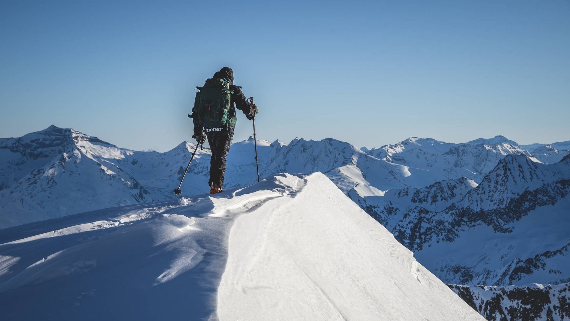 I tour di scialpinismo più belli del Tirolo Orientale Escursionista con zaino sulla cima innevata delle Alpi