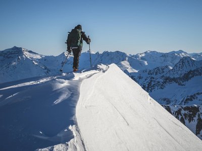Unvergesslicher Skiurlaub im Defereggental Wanderer mit Rucksack auf schneebedecktem Berggipfel in den Alpen