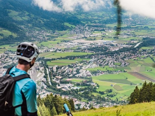 Ausflugsziele im Defereggental Fahrradfahrer blickt von Hügel auf Stadt und grüne Felder im Tal