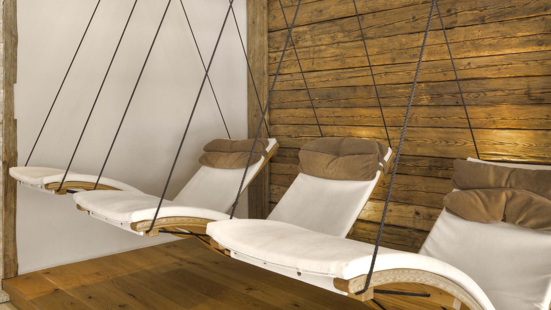 Area adults only del nostro wellness hotel in Austria Sedie a dondolo con cuscini in una stanza accogliente con rivestimento in legno