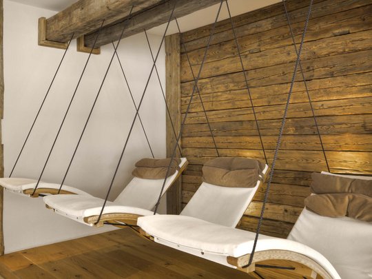Benessere alpino al nostro albergo in Tirolo Sedie a dondolo con cuscini in una stanza accogliente con rivestimento in legno