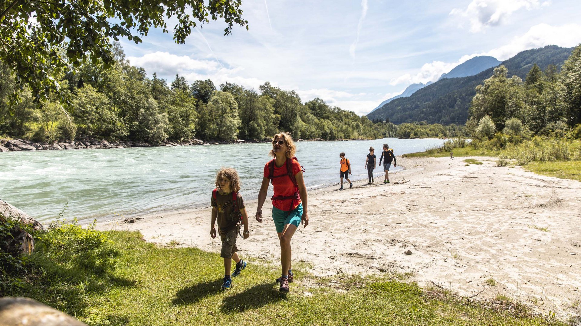 Familienhotel in Osttirol: der Jesacherhof Familie wandert am Flussufer entlang in einer bergigen Landschaft