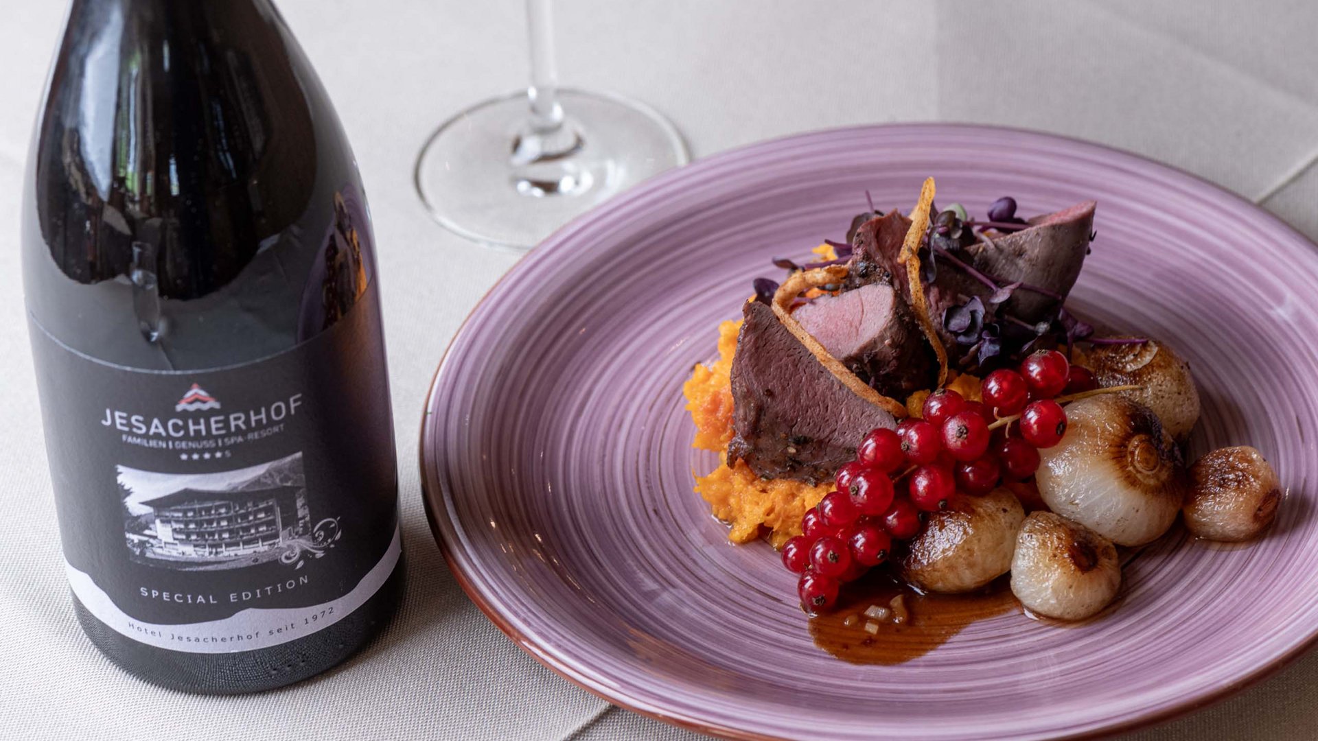 Jesacherhof: Gourmethotel in Österreich Gourmetgericht mit Fleisch, Zwiebeln und roten Johannisbeeren neben Weinflasche