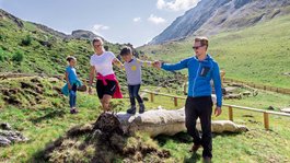 I servizi del nostro hotel per famiglie in Tirolo Famiglia che fa escursione in montagna in una giornata soleggiata