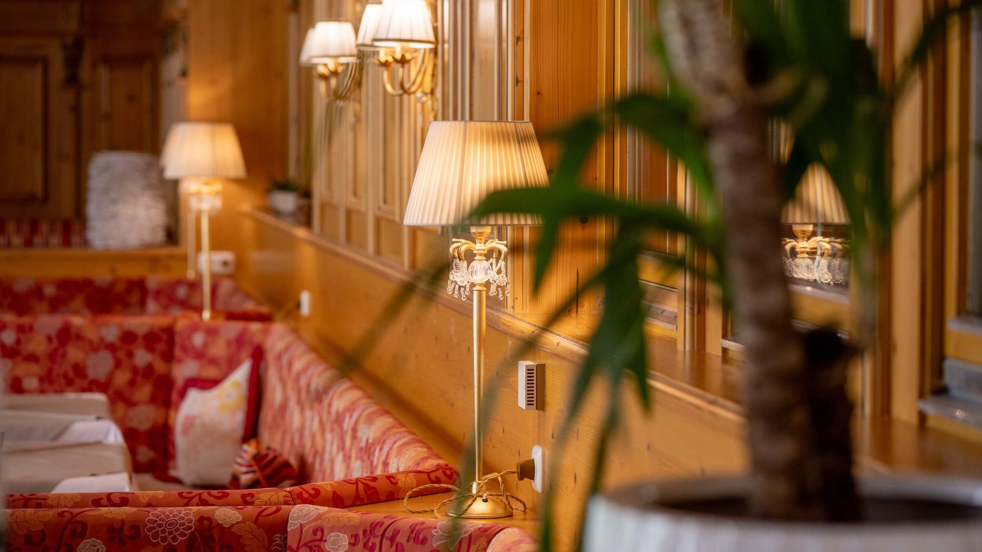 Jesacherhof: Gourmethotel in Österreich Gemütlicher Sitzbereich mit roten Sofas und warmen Lampen in Holzwandumgebung