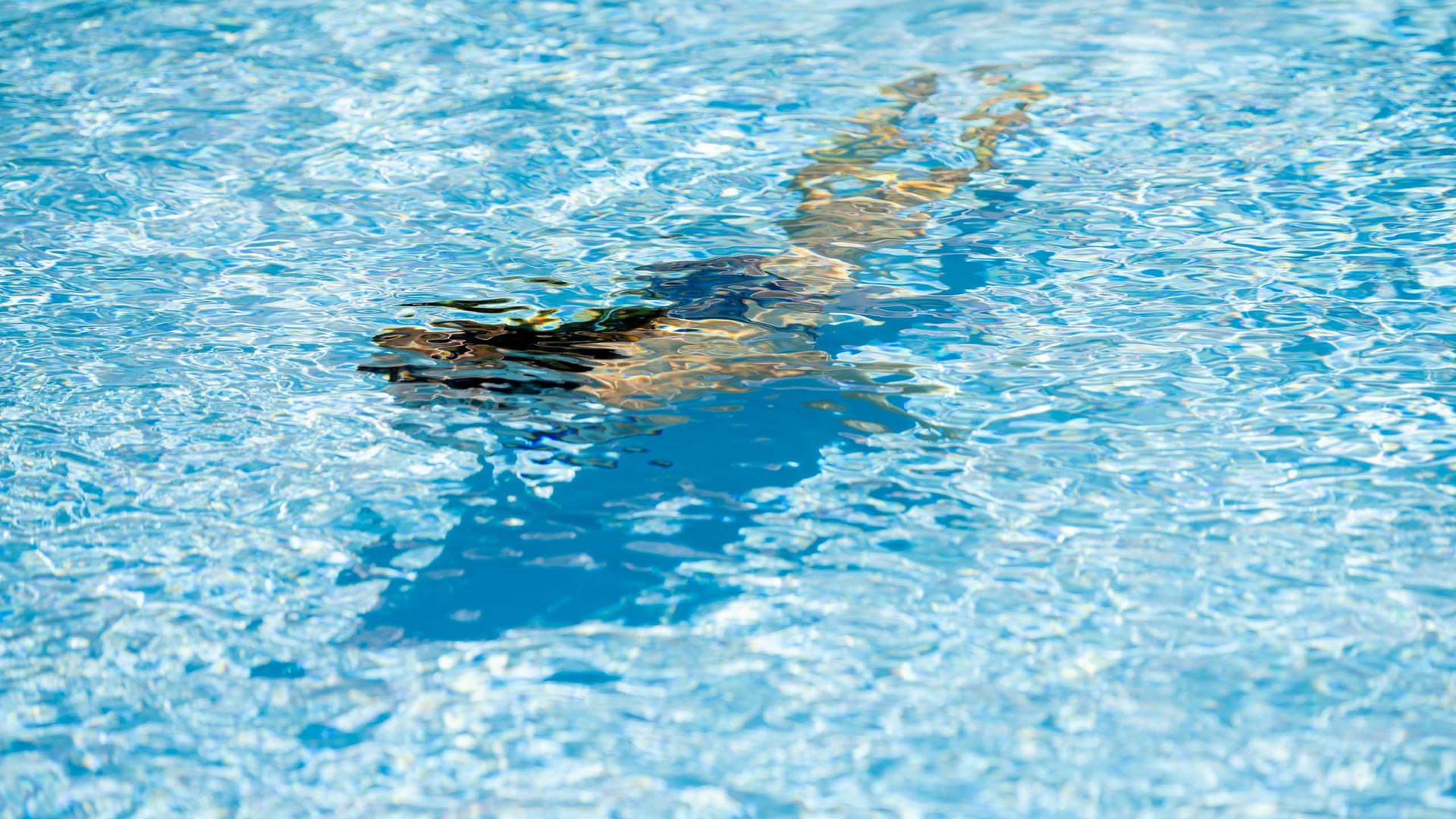 Wellnesshotel im Defereggental: Wohlfühlurlaub vom Feinsten Person schwimmt unter Wasser in klarem blauen Pool