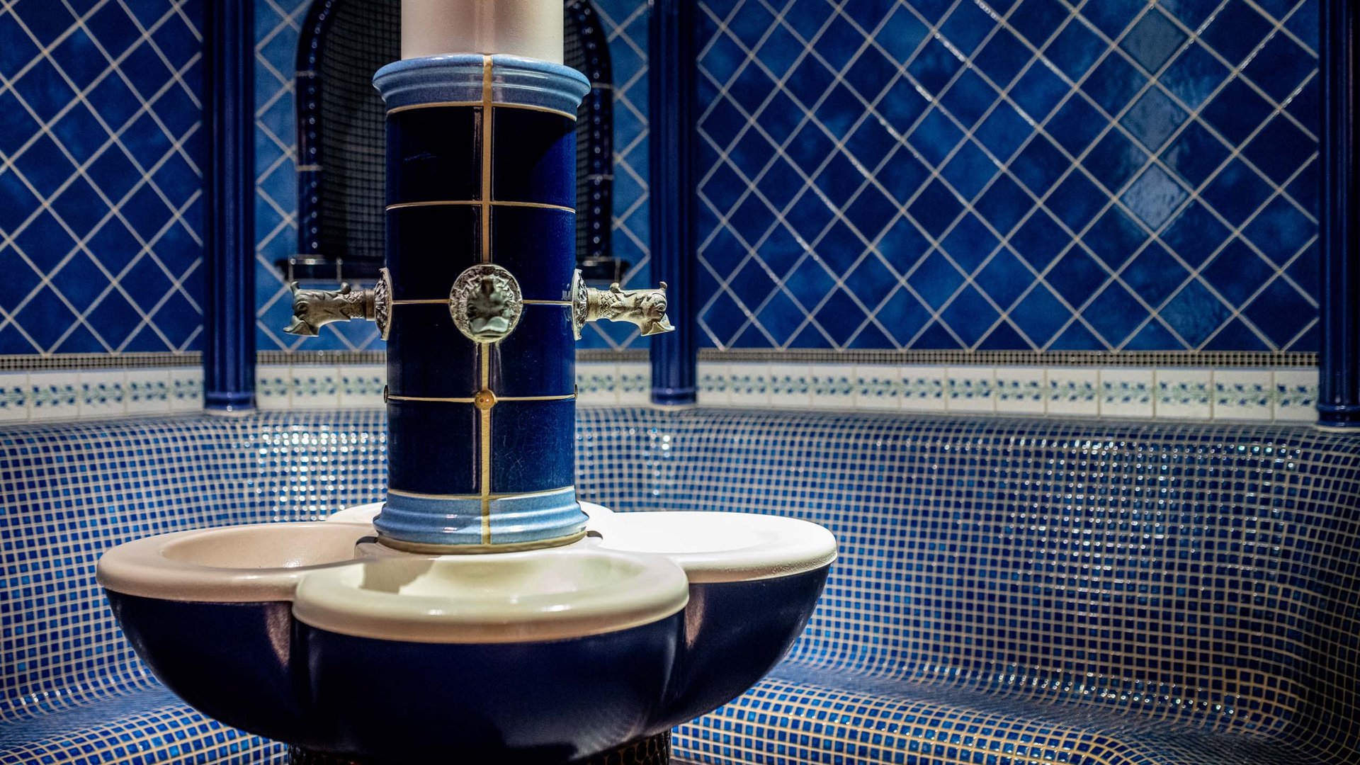 I servizi del nostro hotel per famiglie in Tirolo Interno di bagno di vapore tradizionale con piastrelle blu e fontana d'acqua