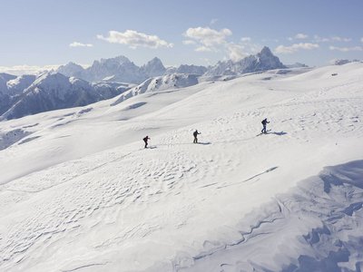Unvergesslicher Skiurlaub im Defereggental Drei Skifahrer in einer schneebedeckten Berglandschaft bei klarem Himmel