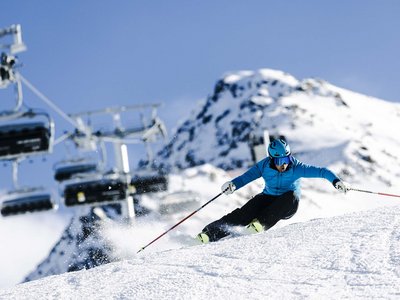 Unvergesslicher Skiurlaub im Defereggental Skifahrer in blauer Jacke fährt schnell auf verschneiter Piste mit Berg im Hintergrund
