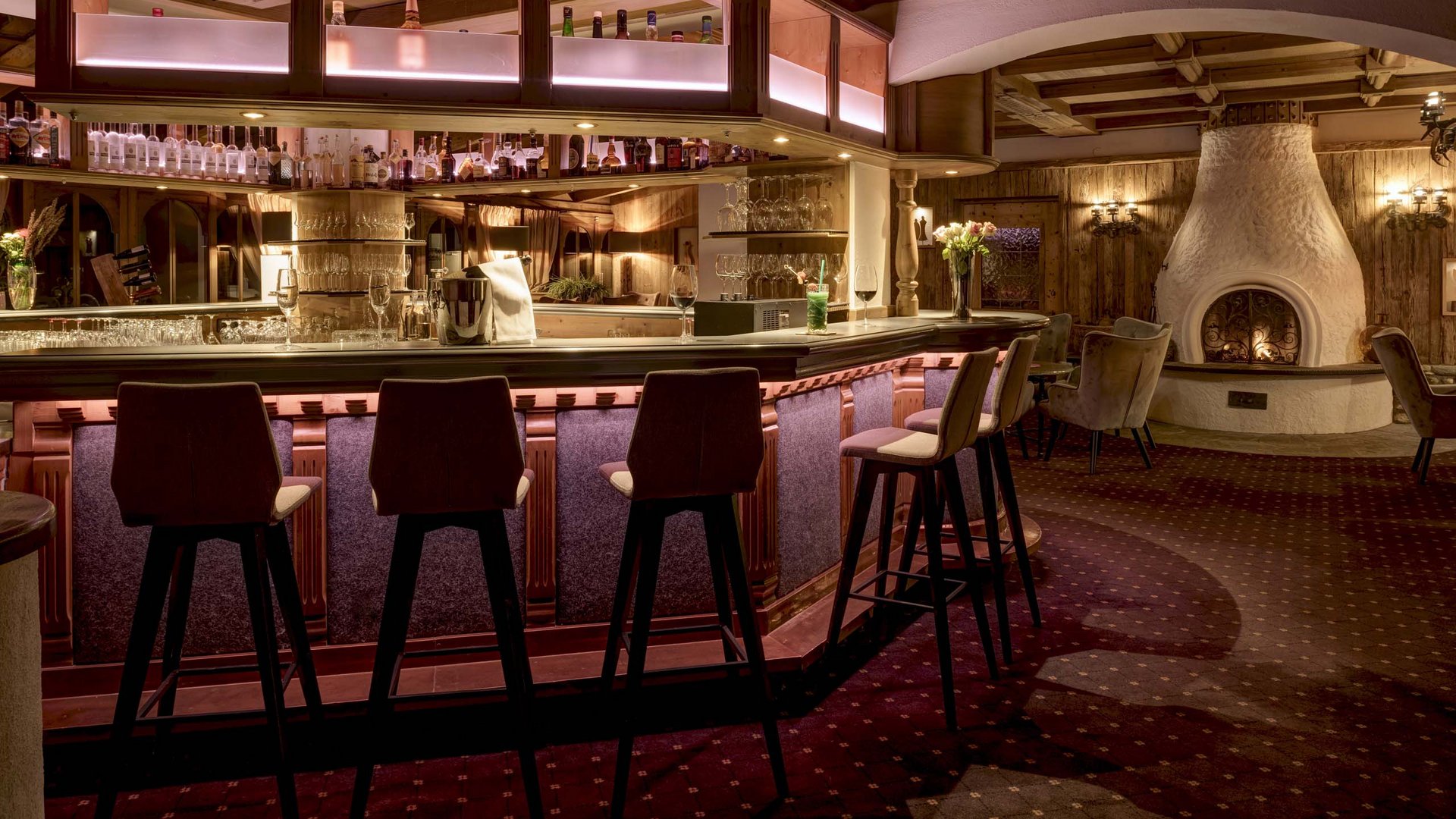 Jesacherhof: Ihr Hotel im Defereggental Gemütliche Hotelbar mit Holztheke, Hockern und Kamin im Hintergrund