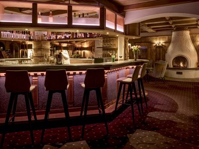 Gourmethotel in Osttirol mit Panoramabar Gemütliche Hotelbar mit Holztheke, Hockern und Kamin im Hintergrund