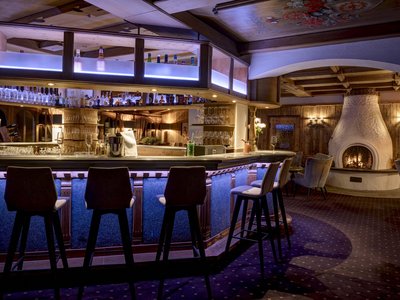 Freie Stellen im Jesacherhof – Hotel in Tirol Gemütliche Bar mit Kamin und Holzmöbeln in warmem Licht