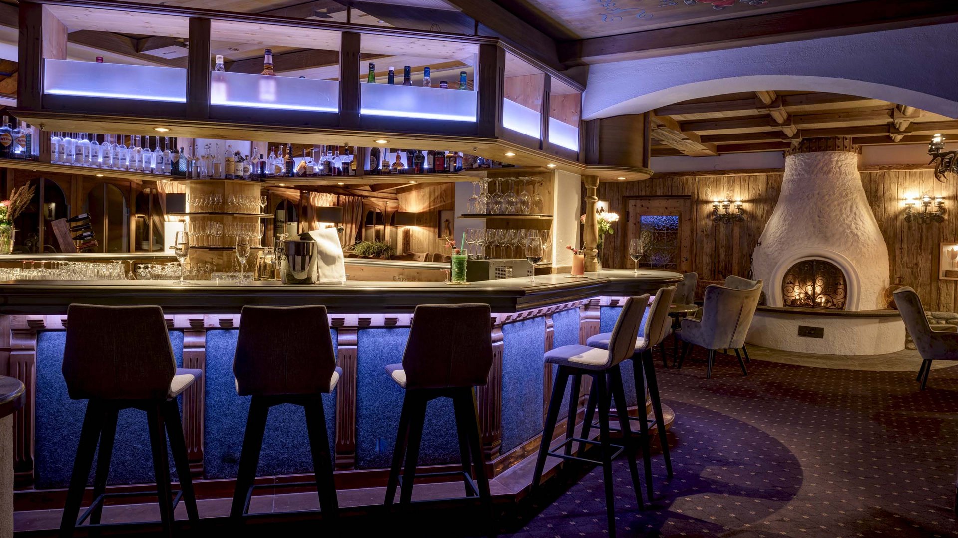 I servizi del nostro hotel per famiglie in Tirolo Bar accogliente con camino e arredi in legno sotto luce calda