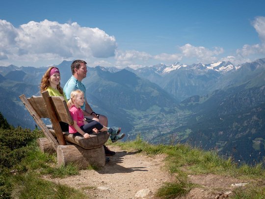 Defereggental: Sehenswürdigkeiten und Ausflugsziele Familie sitzt auf Holzbänken mit Blick auf Alpen und Tal