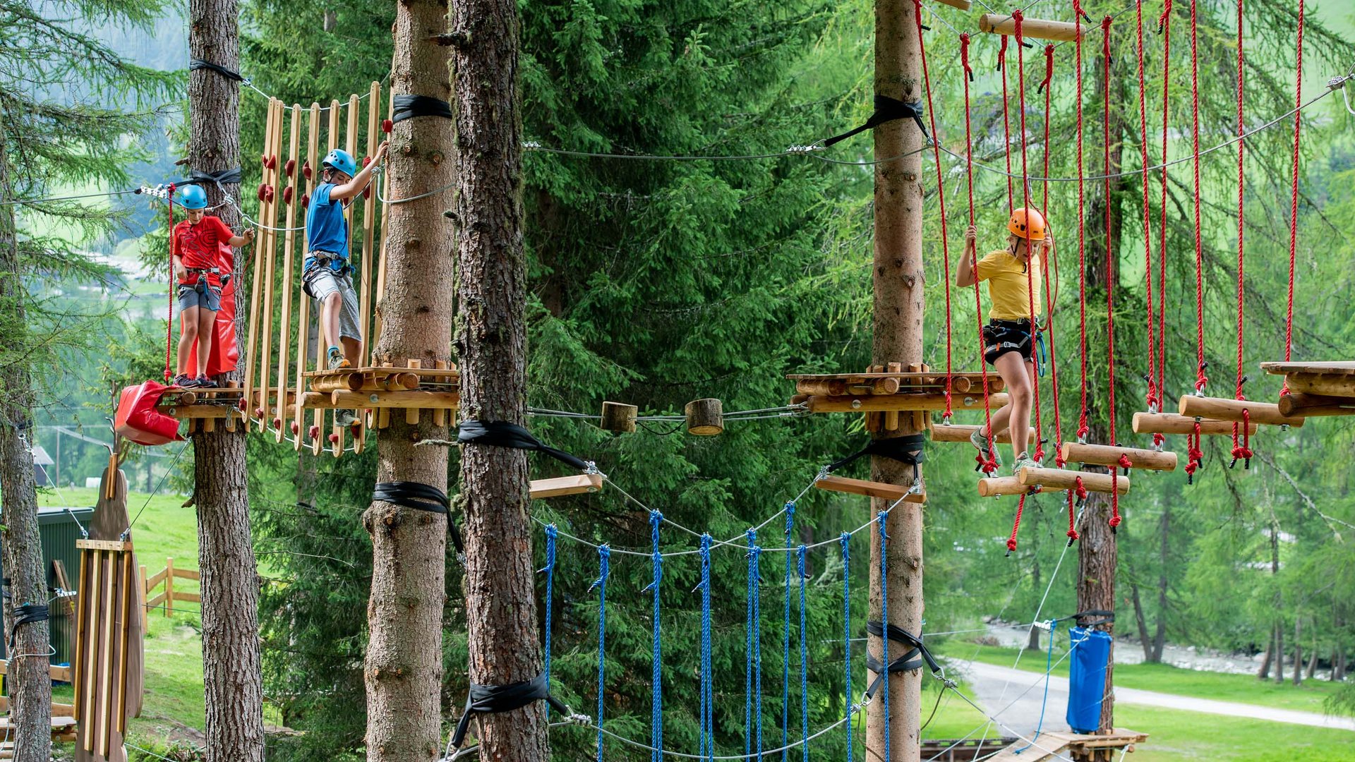 Unvergesslicher Skiurlaub im Defereggental Kinder klettern im Hochseilgarten zwischen Bäumen mit Sicherheitsausrüstung