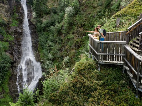 Ausflugsziele im Defereggental Familie betrachtet Wasserfall von einem Holz-Aussichtsplattform im Wald