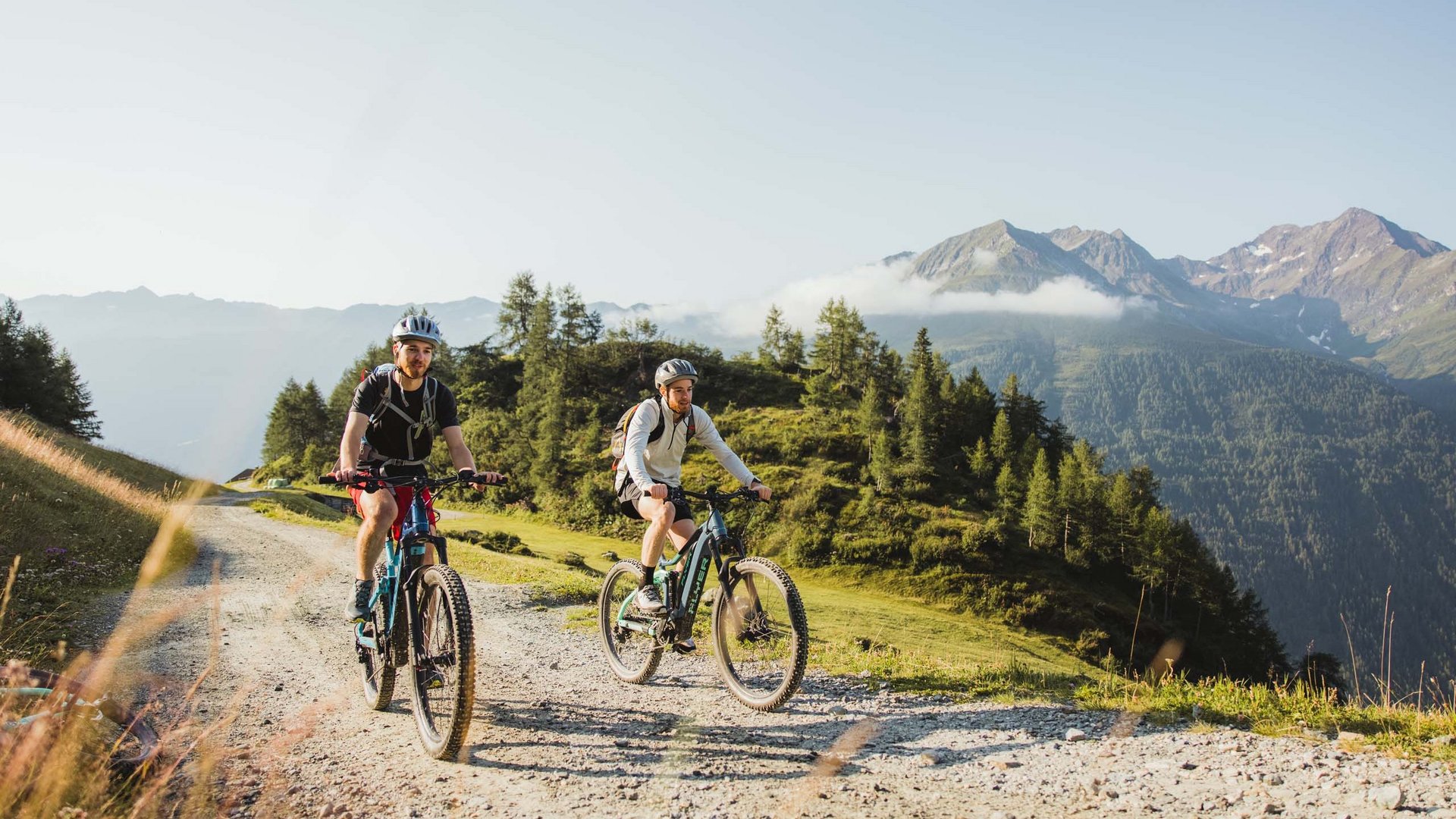 Trekking in Tirolo, Austria: allo Jesacherhof Due uomini in mountain bike su un sentiero di montagna con cielo limpido