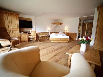Freude verschenken: unser Hotel in Osttirol mit Wellness Gemütliches Hotelzimmer mit Holzmöbeln, Doppelbett und Sitzbereich