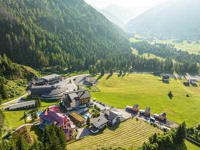 Posizioni aperte al nostro hotel a 4 stelle S in Austria Veduta aerea di un villaggio di montagna con foreste e prati al sole