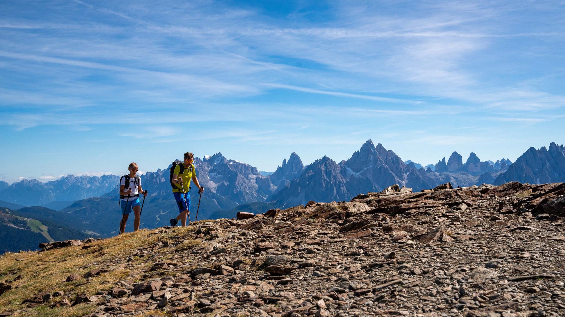 Trekking in Tirolo, Austria: allo Jesacherhof Due escursionisti su un sentiero di montagna con vista su cime rocciose e cielo blu