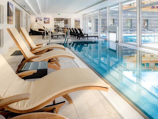 Wellnesshotel im Defereggental: Wohlfühlurlaub vom Feinsten Innenpool mit Liegestühlen und großen Fenstern zur Außenseite