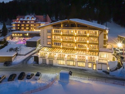 Jesacherhof: Ihr Hotel im Defereggental Beleuchtetes Hotel Jesacher im verschneiten Winterabend mit geparkten Autos