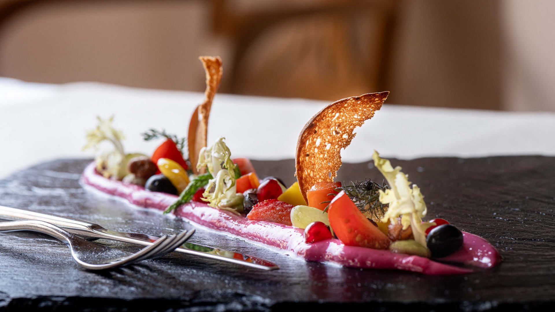 Jesacherhof: Gourmethotel in Österreich Fein angerichtete Gourmet-Vorspeise mit frischen Zutaten und knusprigem Brot auf schwarzem Stein