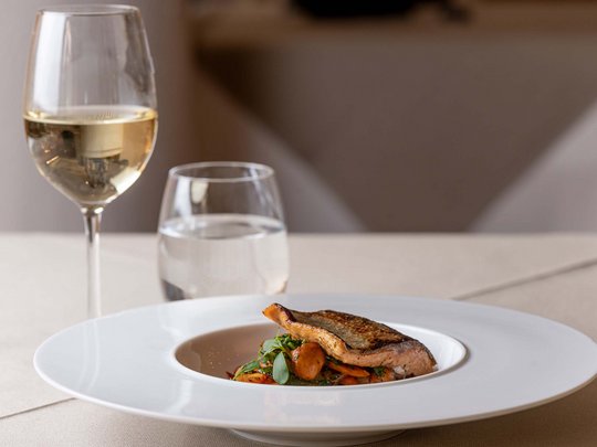 Jesacherhof: Gourmethotel in Österreich Gebratenes Lachsfilet mit Gemüse, Weißwein und Wasserglas auf gedecktem Tisch
