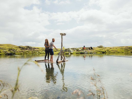 Jesacherhof: Ihr Hotel im Defereggental Paar auf hölzernem Floß über ruhigem See in ländlicher Umgebung