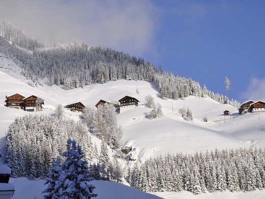 St. Jakob in Defereggen: escursioni e gite Baite e alberi coperti di neve su una montagna sotto un cielo blu