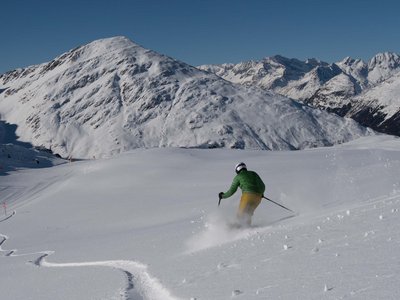 Unsere Tipps für einen Wanderurlaub in Osttirol Skifahrer fährt auf frischem Pulverschnee in den Alpen bei klarem Himmel