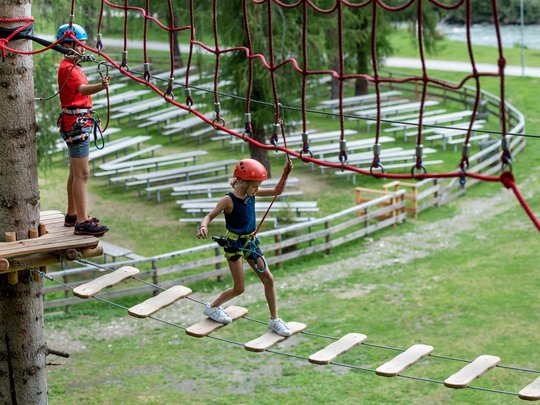 Defereggental: Sehenswürdigkeiten und Ausflugsziele Kind und Trainer mit Helm beim Klettern im Hochseilgarten