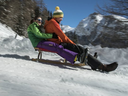 Family hotel in East Tyrol: the Jesacherhof Two people sledding together on snow with mountains in the background