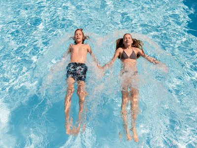 Benessere alpino al nostro albergo in Tirolo Due bambini nuotano rilassati mano nella mano in piscina