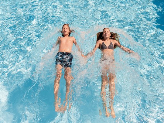 Wellnesshotel im Defereggental: Wohlfühlurlaub vom Feinsten Zwei Kinder schwimmen entspannt Hand in Hand im Schwimmbad