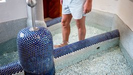 I servizi del nostro hotel per famiglie in Tirolo Persona in piedi in vasca Kneipp con piastrelle blu e acqua fino alle ginocchia