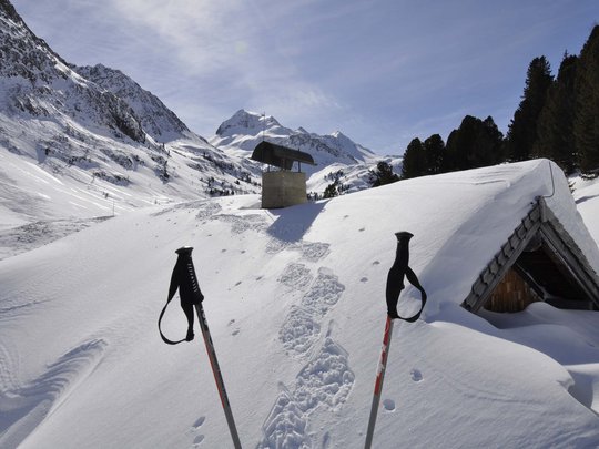Jesacherhof: Ihr Hotel im Defereggental Schneebedeckte Hütte und Wanderstöcke in den Alpen mit Bergpanorama