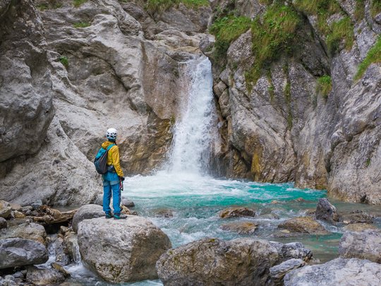Ausflugsziele im Defereggental Wanderer steht auf Felsen vor kleinem Wasserfall in felsiger Berglandschaft