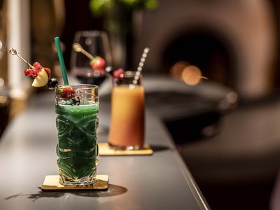 Gourmethotel in Osttirol mit Panoramabar Tiki-Glas mit grünem Cocktail und Fruchtspieß auf Bar