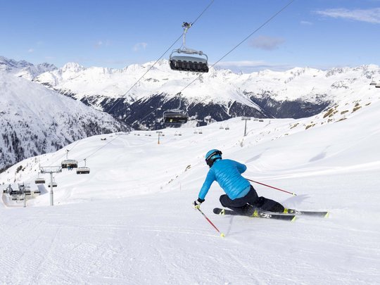 Jesacherhof: Ihr Hotel im Defereggental Skifahrer in blauer Jacke fährt auf verschneiter Piste in den Alpen
