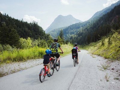 Trekking in Tirolo, Austria: allo Jesacherhof Famiglia va in bicicletta su strada di montagna circondata da boschi