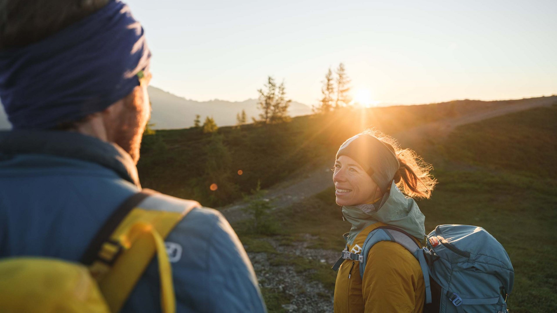 Unvergesslicher Skiurlaub im Defereggental Zwei Wanderer mit Rucksäcken im Sonnenuntergang in den Bergen