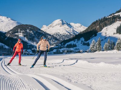 Unvergesslicher Skiurlaub im Defereggental Zwei Langläufer auf verschneiter Loipe mit Bergen und blauem Himmel im Hintergrund