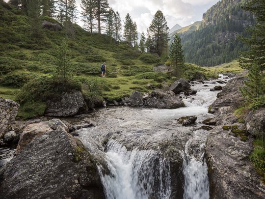 Ausflugsziele im Defereggental Berglandschaft mit Bach, Wasserfall und Wanderer im Wald