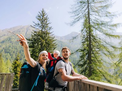Our tips for a hiking holiday in East Tyrol Family hiking with baby in carrier in mountainous forest area with pine trees